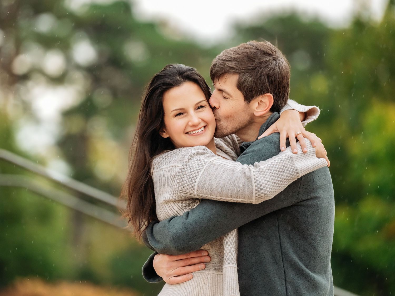 Two people share a romantic moment in a lush garden setting with greenery and trees surrounding them at Lake Como. Engagement Sessions Minn.