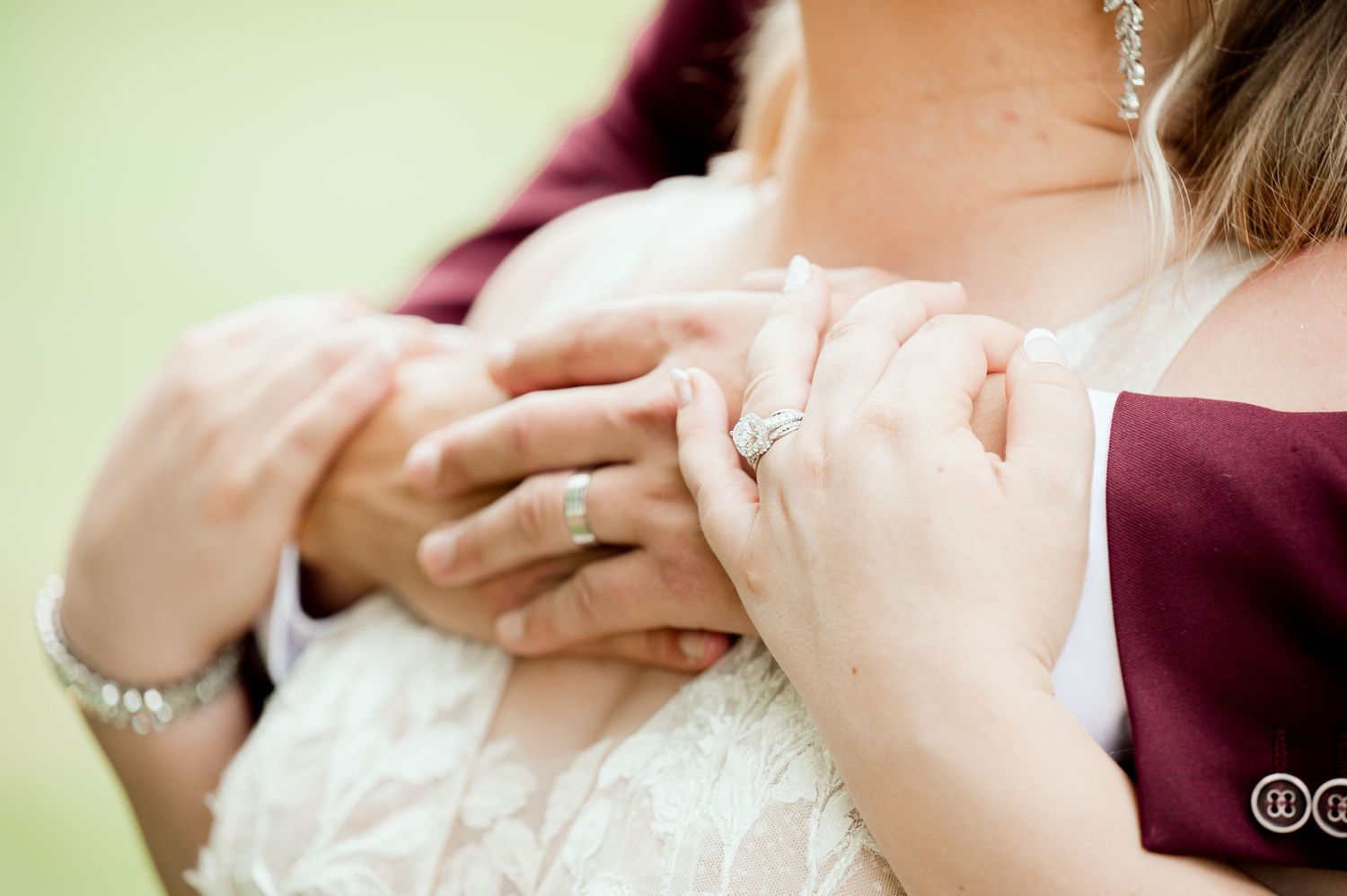 Close-up shot of hands with jewelry adjusting a delicate white lace dress with burgundy accents.
