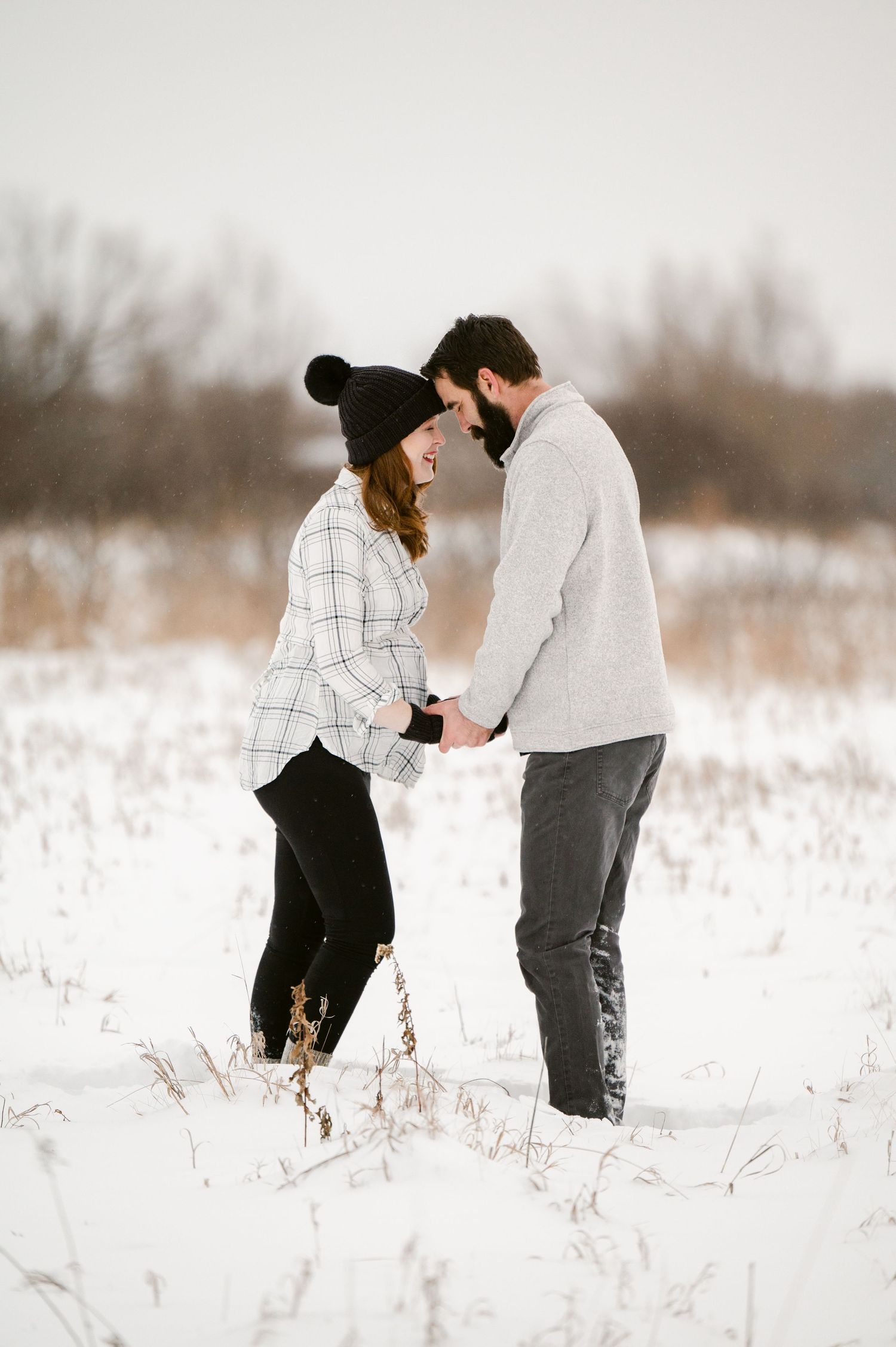 The Clark’s romantic winter maternity photoshoot series in Foreston MN,  in warm layers sharing intimate moments in snowy field.