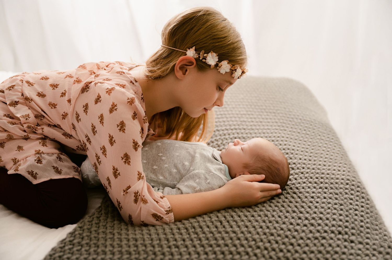 A delicate moment captured between parent and baby lying on a textured gray blanket.