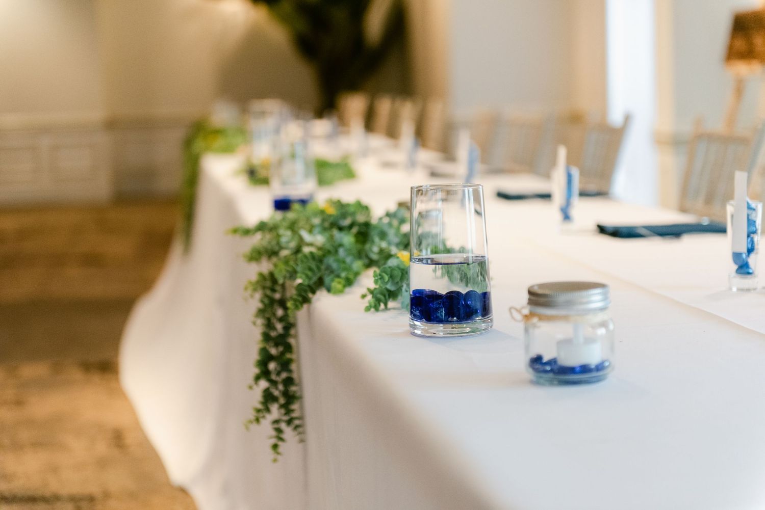 Central MN Wedding Photos | Elegant wedding reception table with white linen, blue floral mason jar centerpieces and greenery.