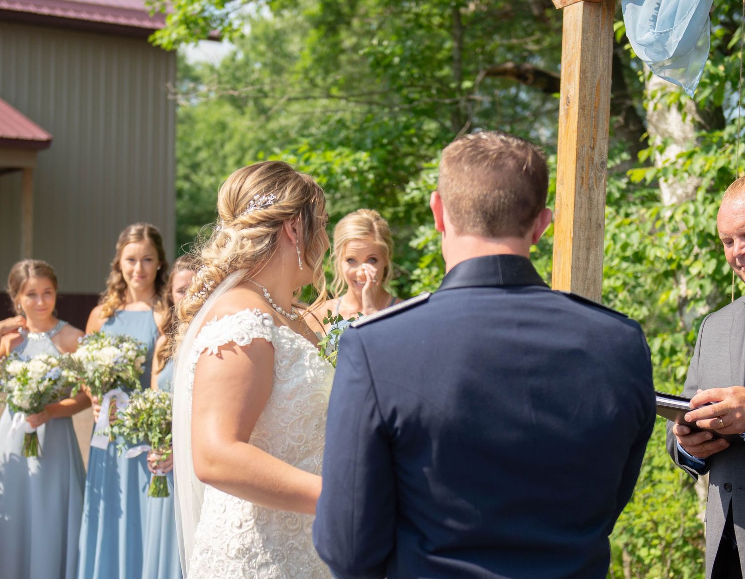 Side view of wedding ceremony with wooden arch and guests seated on white chairs. Zimmerman MN Weddings