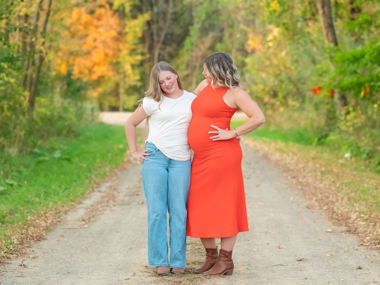 In central Minnesota Two people share a laugh while standing together on a dirt path surrounded by autumn foliage. Maternity Session