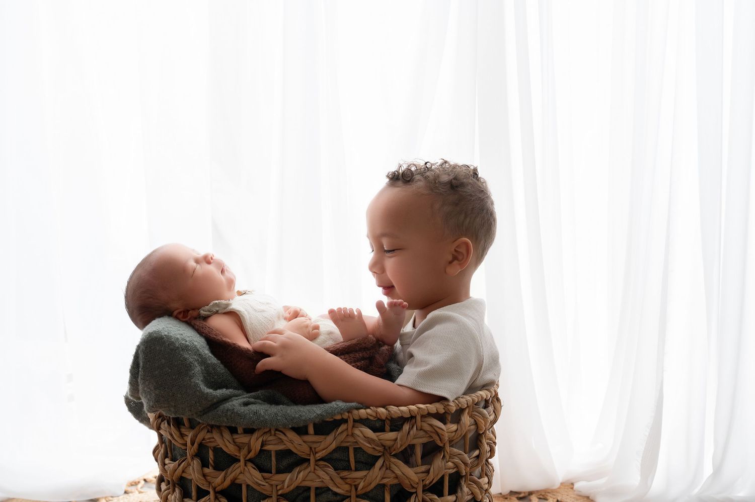 Minnesota Best newborn photos - A baby lies on their back during a newborn photography session with soft white curtains in the background.