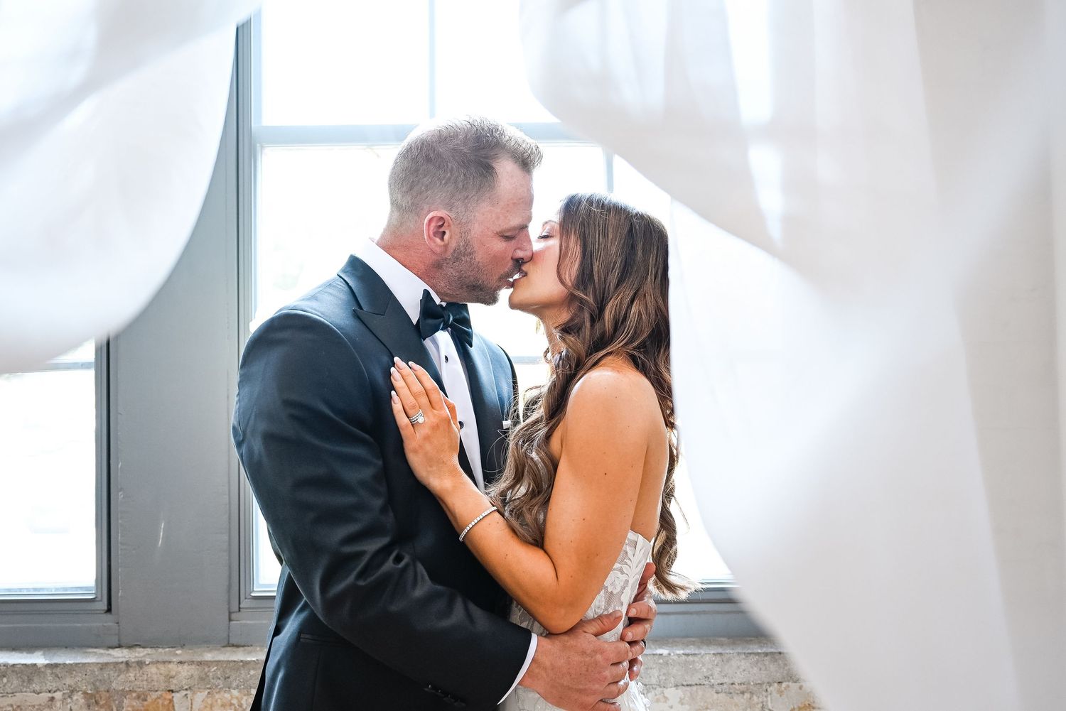 A romantic first look moment unfolds in a bright industrial wedding venue.