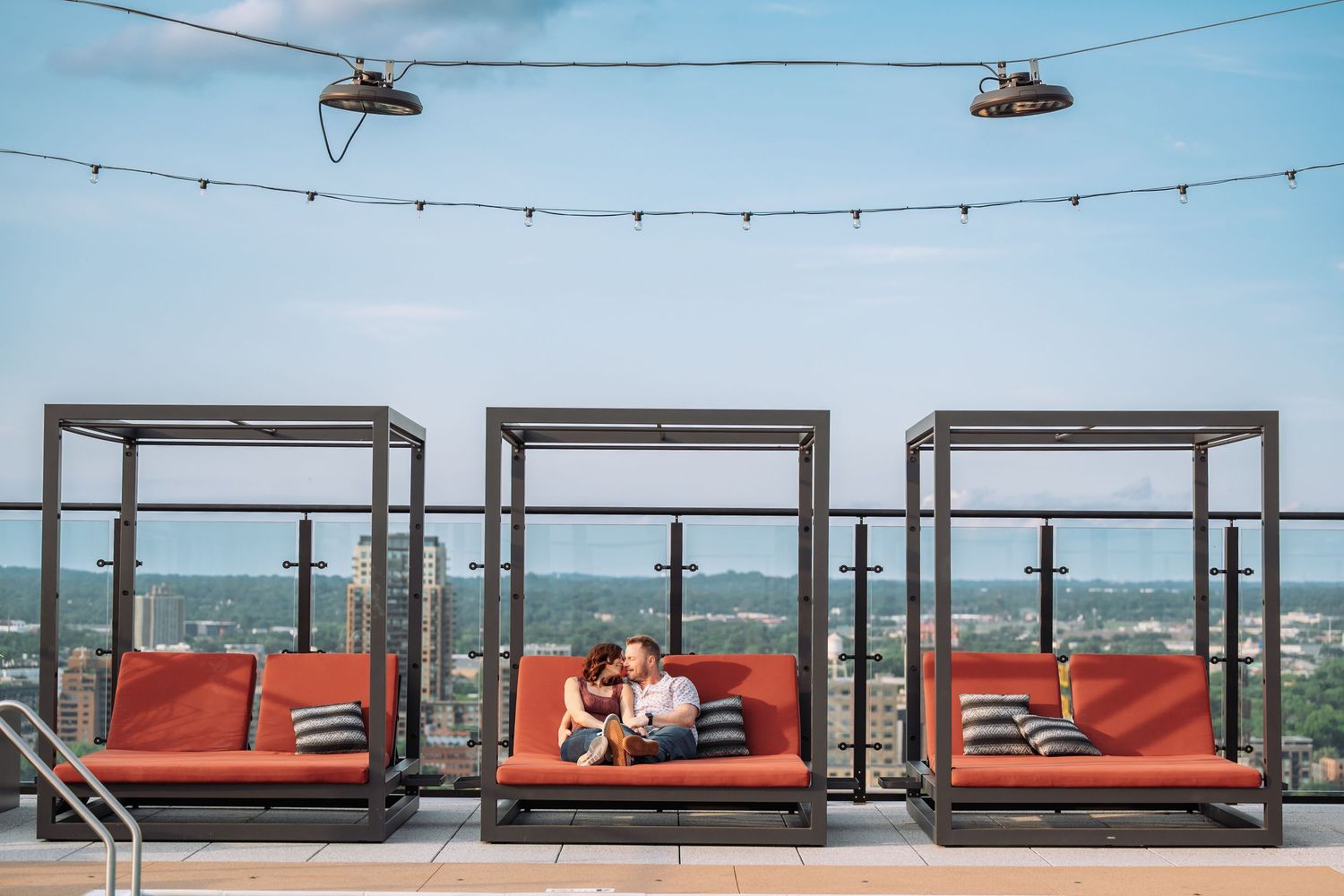 A rooftop terrace with string lights and orange lounge seating offers panoramic views of the surrounding landscape.