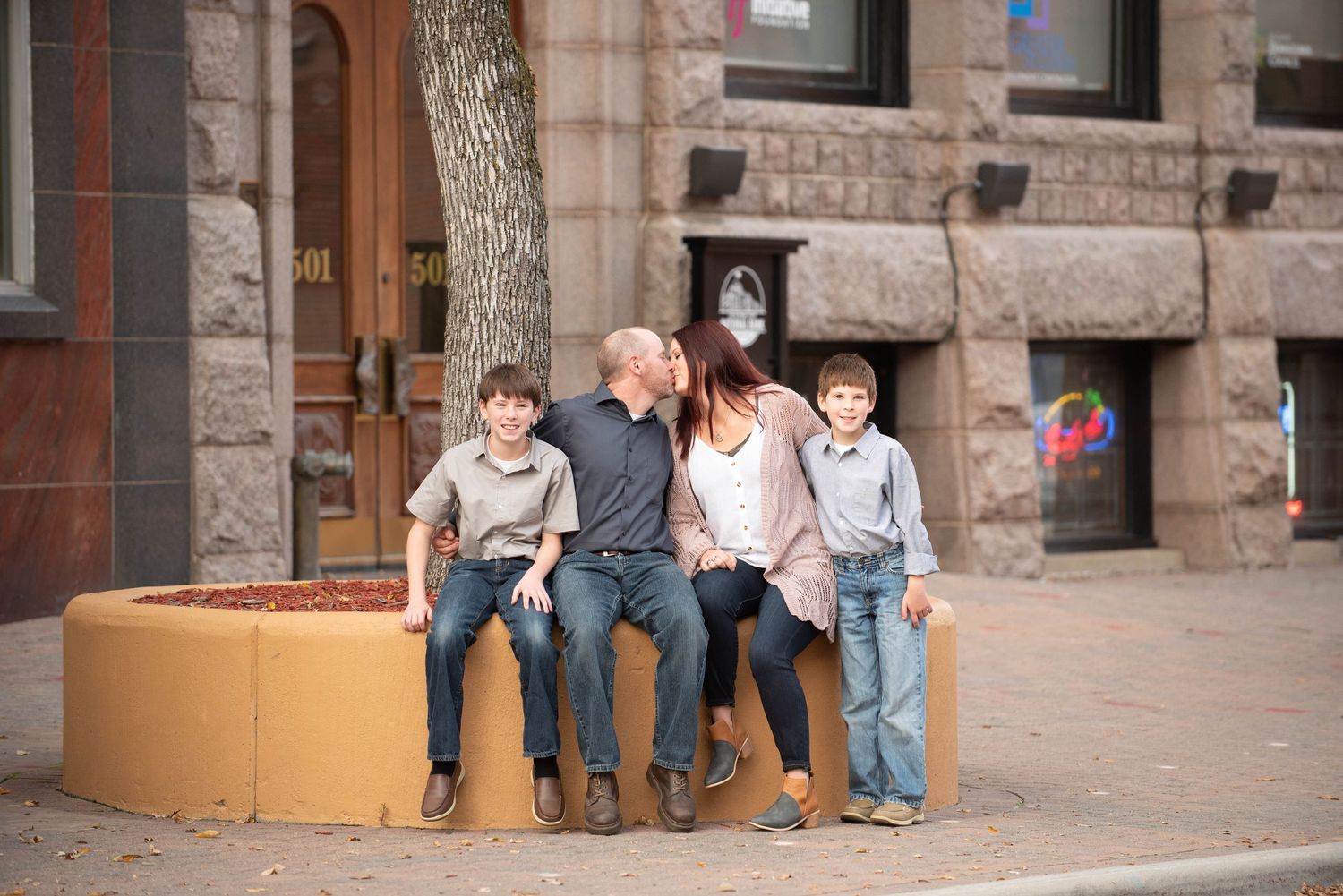 People sitting on stone steps in front of a historic building with arched doorways and stone walls.