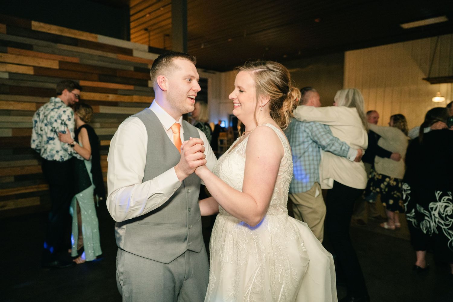 Bride and groom laugh and dance together joyfully on the wedding reception dance floor.