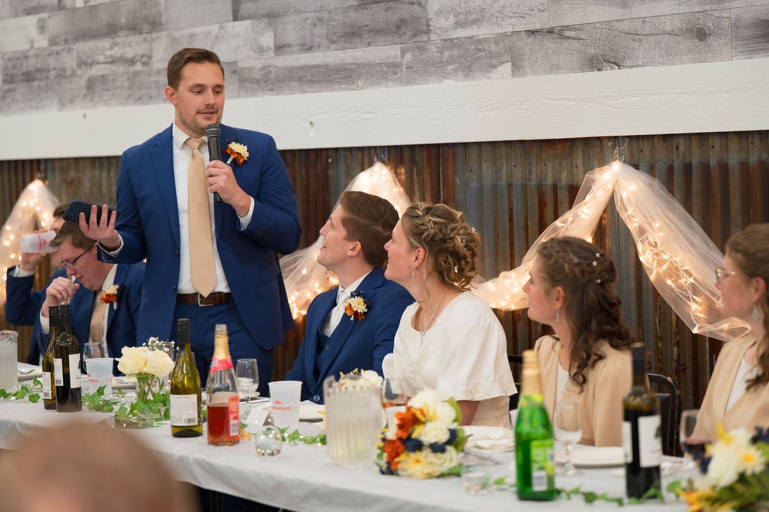 Wedding guests enjoy a lively celebration with drinks and laughter during an outdoor reception.