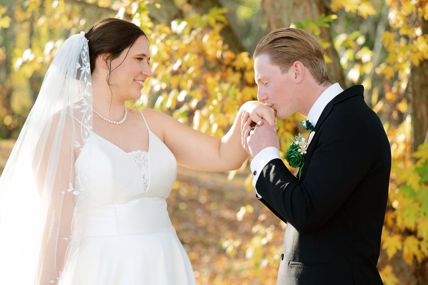 Joyful wedding couple shares intimate moments against a backdrop of golden autumn leaves.