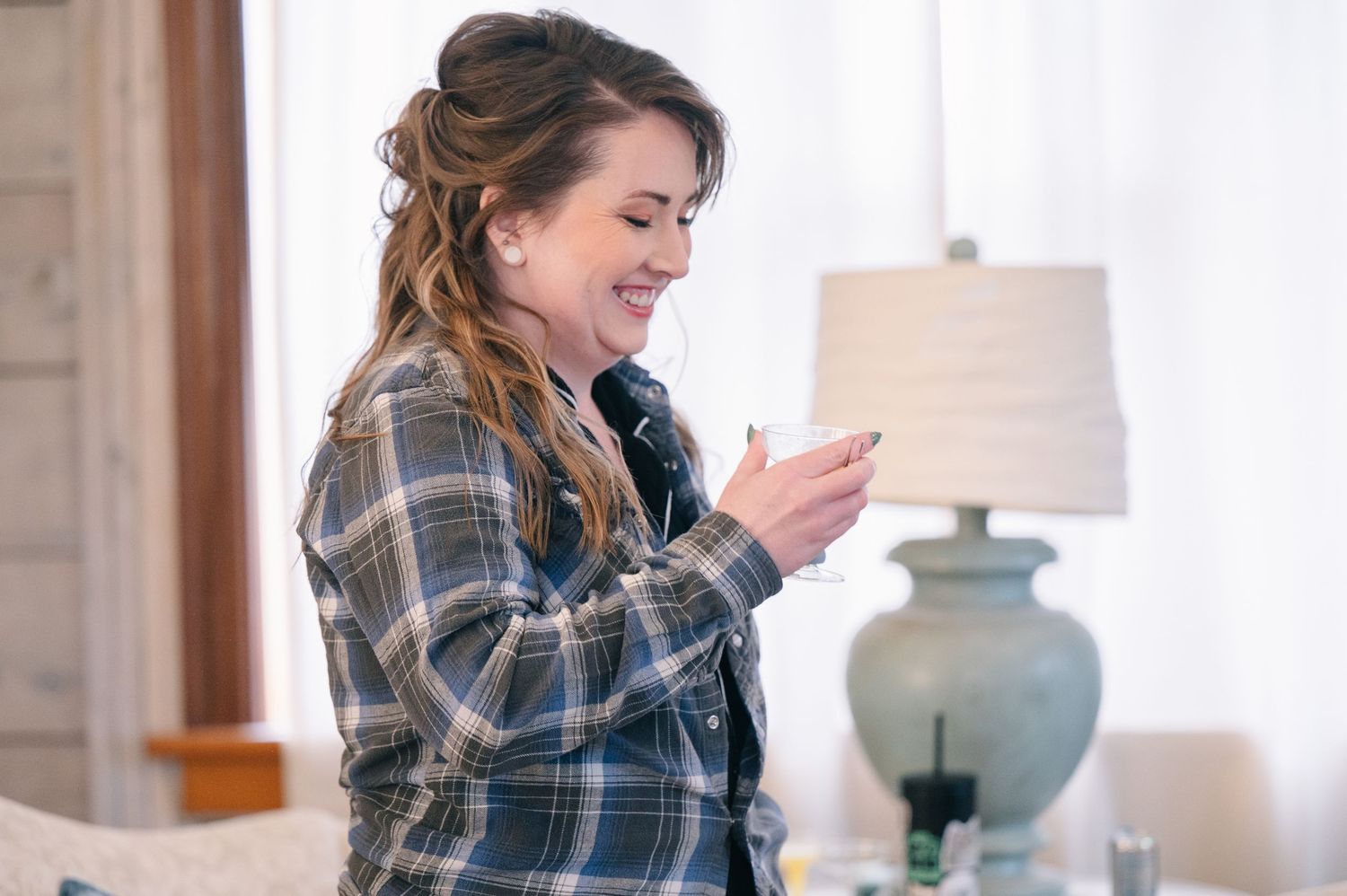 crooked willow weddings Smiling bride in plaid flannel reads a note while getting ready on her wedding morning.