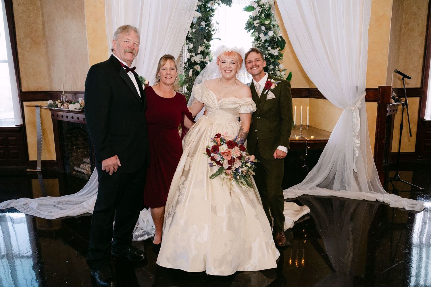 Central MN Wedding Photos | Bride in ivory ball gown poses with groom and family at Christmas wedding reception.
