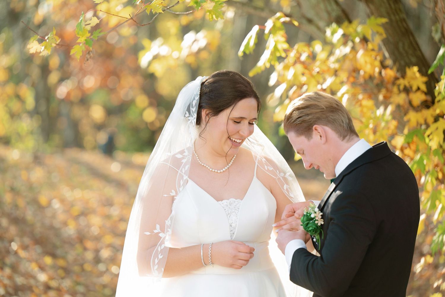 Romantic wedding moment captured in a wooded setting with autumn foliage.