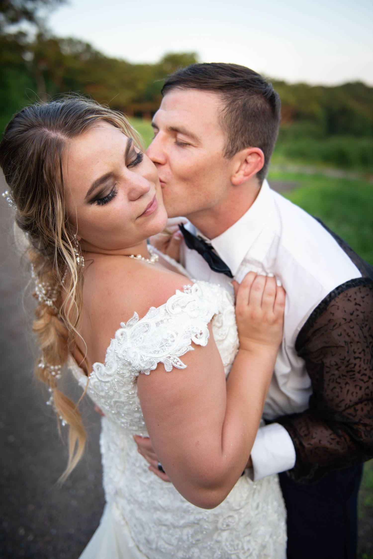 An intimate moment between newlyweds sharing a tender kiss against a natural outdoor backdrop.  Zimmerman MN Weddings