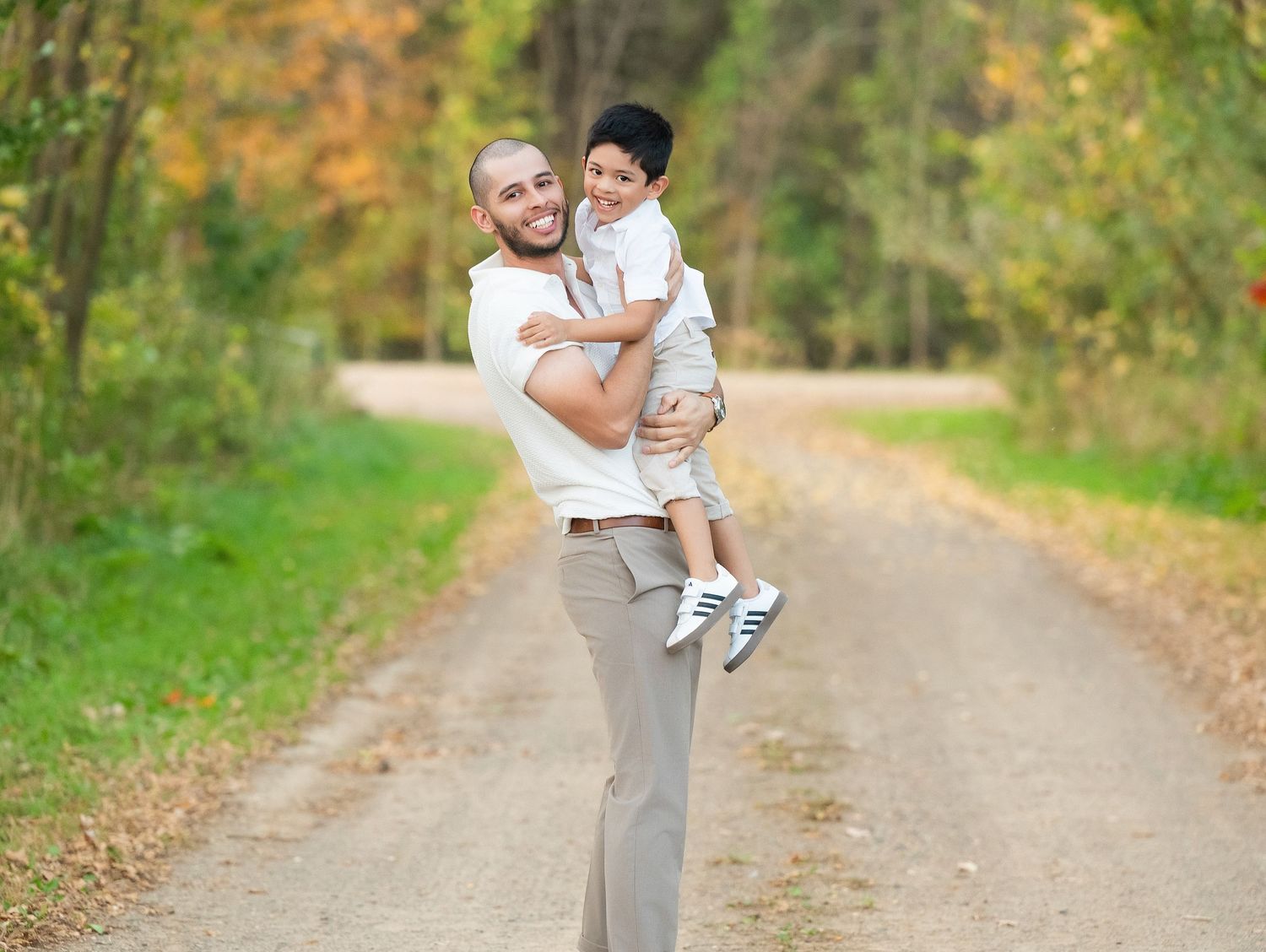 A parent and child share a playful moment on a tree-lined autumn path while enjoying outdoor activities together.