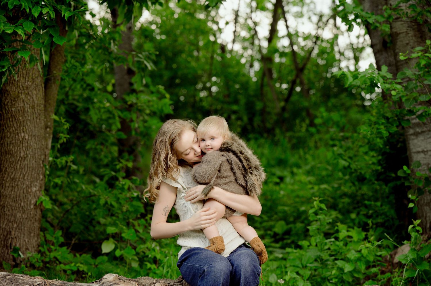 A tender moment captured in a lush green forest setting with natural earthtone clothing.