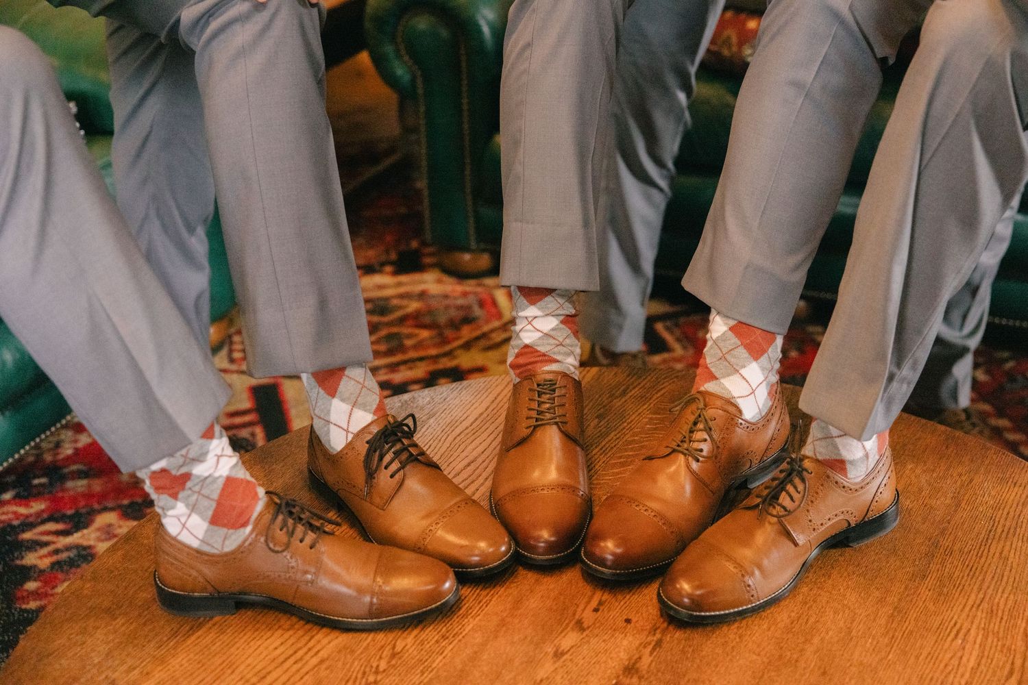 Groomsmen wearing matching argyle socks and brown leather oxford shoes with gray trousers.