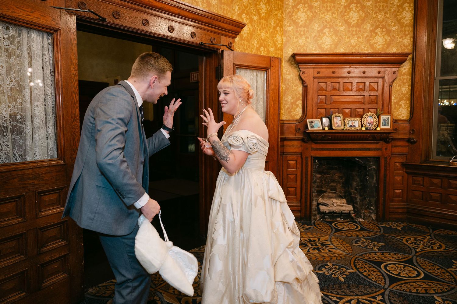 Central MN Wedding Photos | Bride and groom share an excited first look reaction in an elegant wood-paneled room with a fireplace.