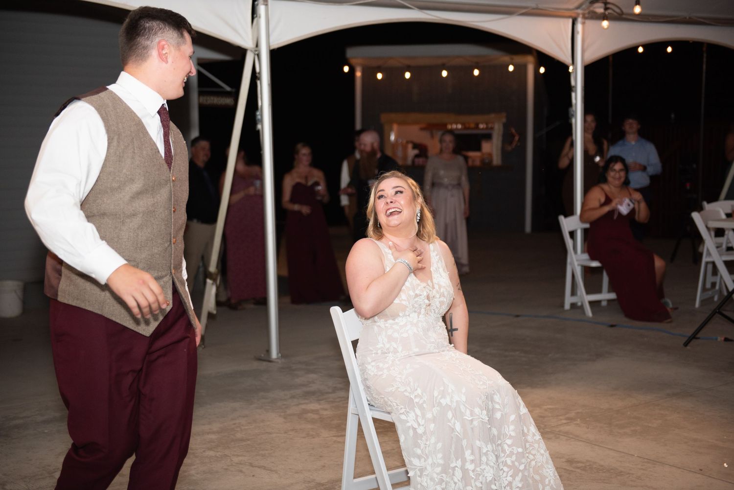 A touching moment during a wedding celebration under a tent as guests share an emotional dance.