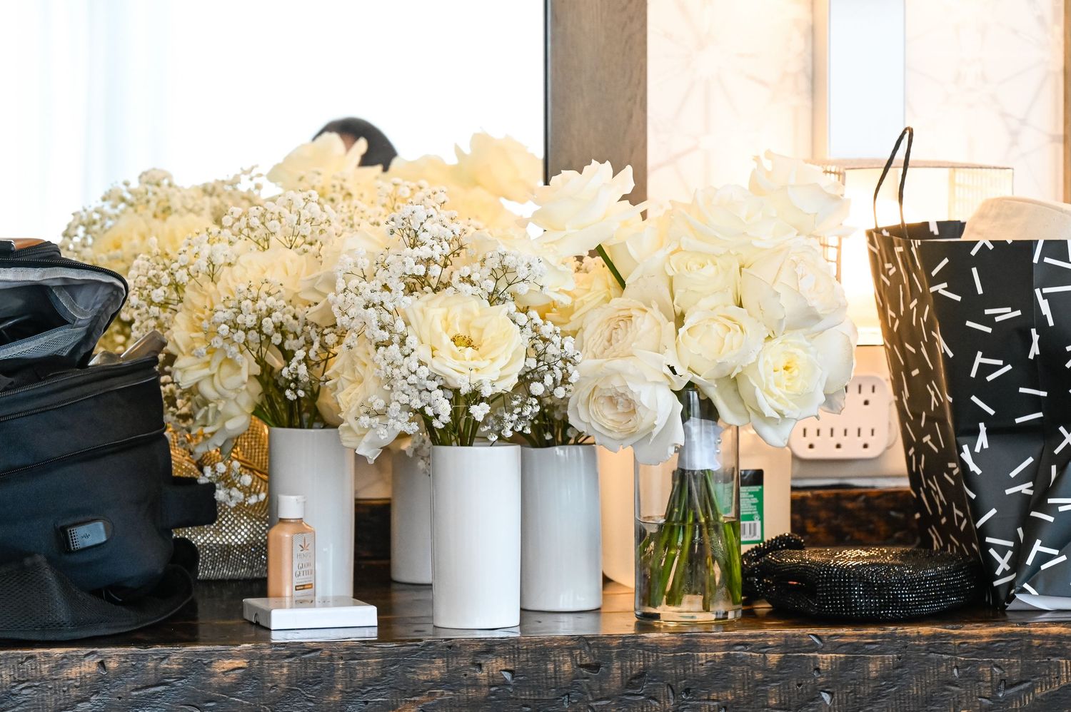 White floral arrangements in ceramic vases displayed in a row against a dark background.