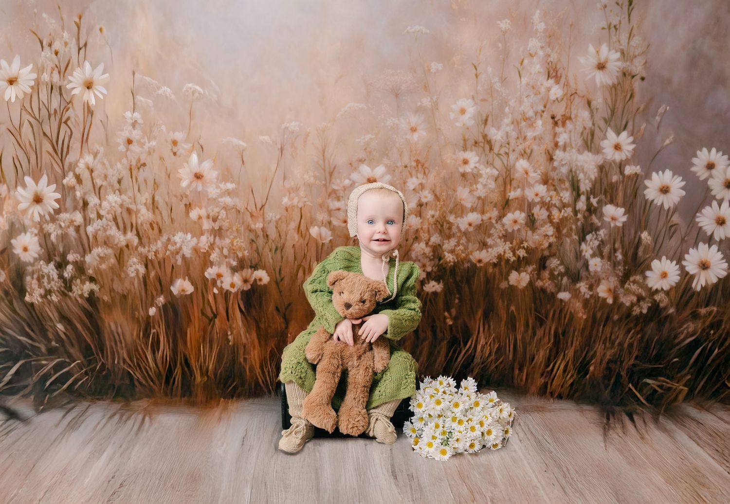Toddler in green outfit hugging a teddy bear, seated before a floral meadow backdrop with daisies. mother day photoshoot