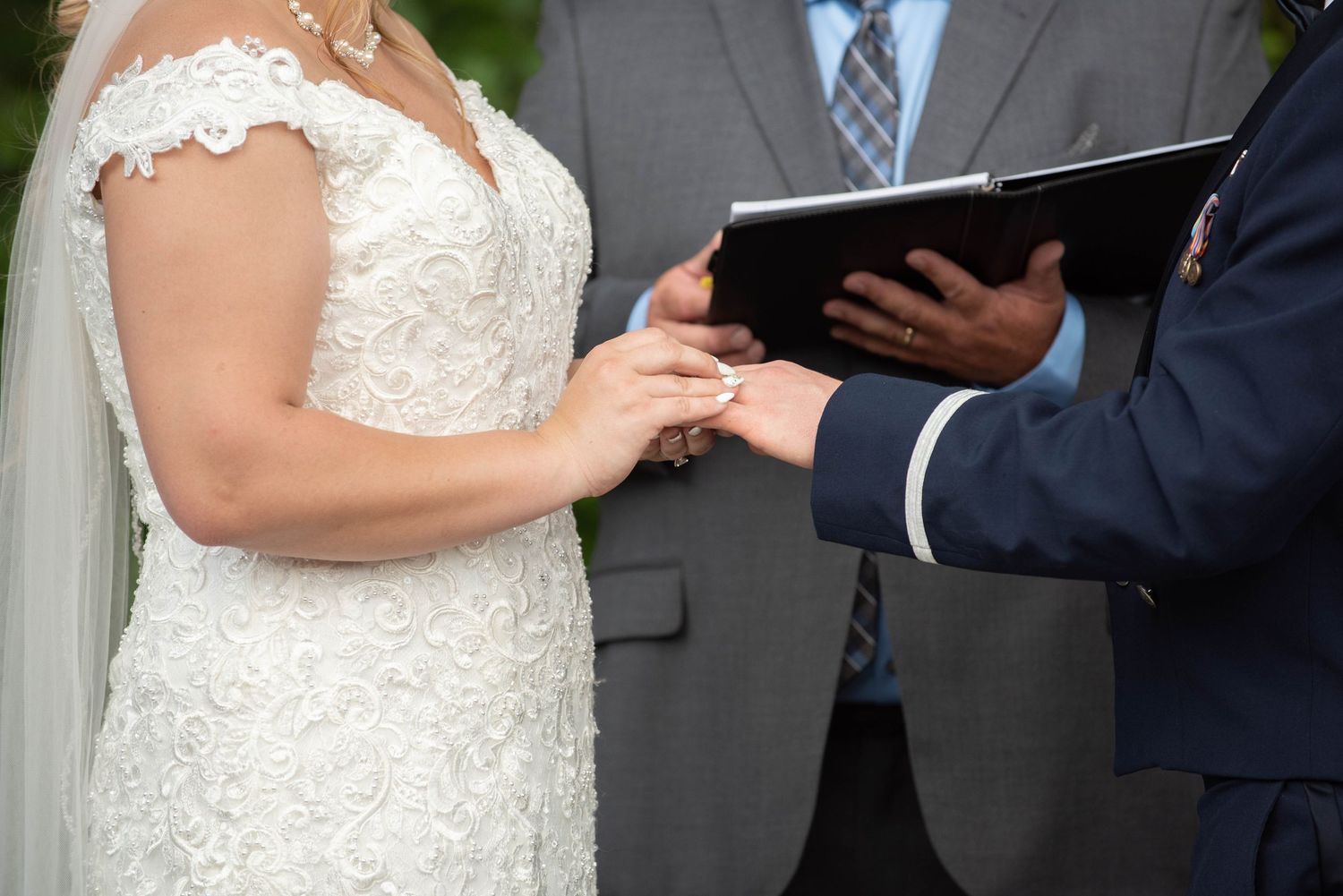 Close-up of ring exchange during outdoor wedding ceremony with white lace bridal gown. Zimmerman MN Weddings