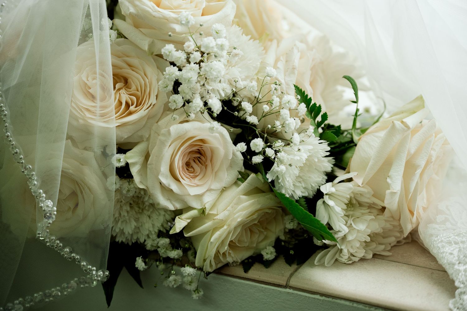 Elegant white roses and baby's breath floral arrangement with delicate lace details.