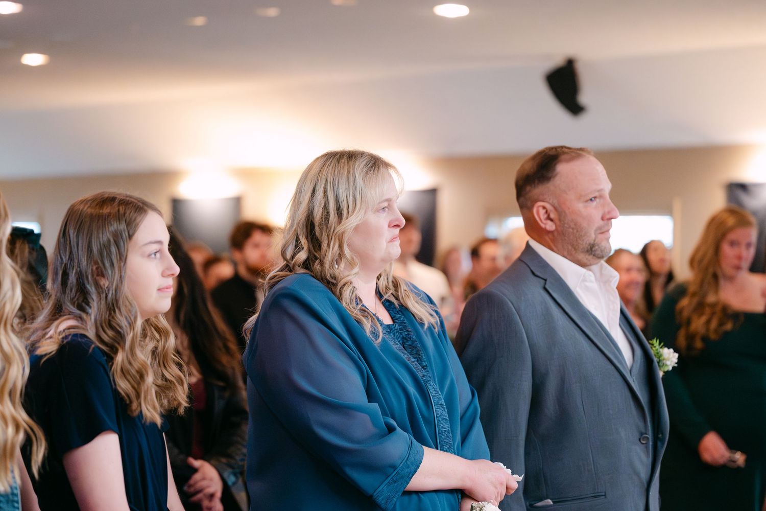 Wedding ceremony attendees standing in rows during an indoor celebration.