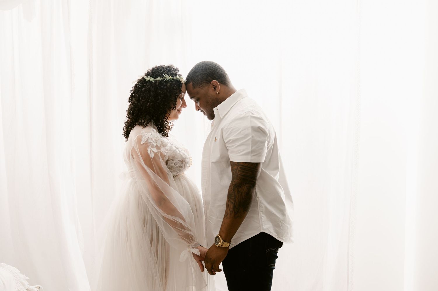 A romantic wedding photo shows a happy couple embracing tenderly against a white curtained background.