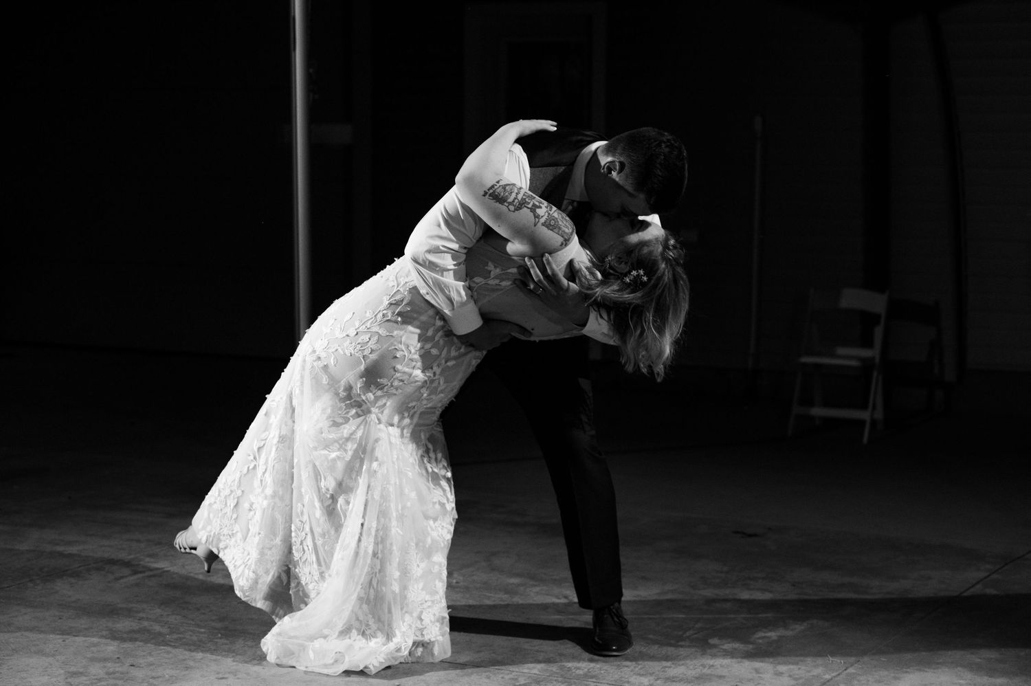 Black and white photo of couple performing romantic dance dip in formal attire.