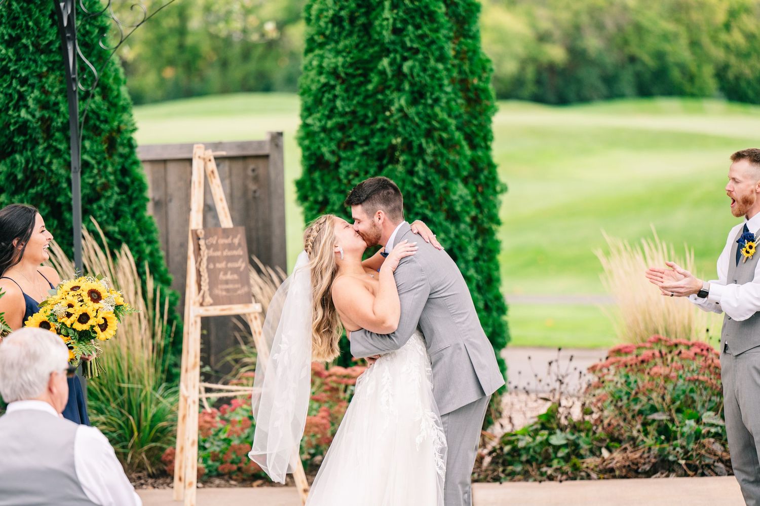 Central MN Wedding Photos - Bride and groom sharing first kiss at outdoor wedding ceremony.