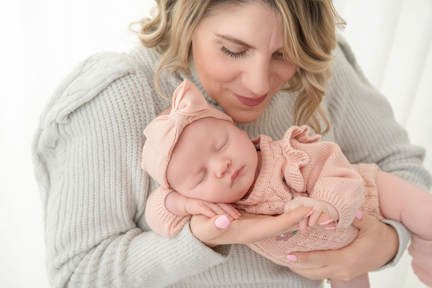 A tender newborn photography session featuring soft gray and white tones with a sleeping baby and gentle embraces.
