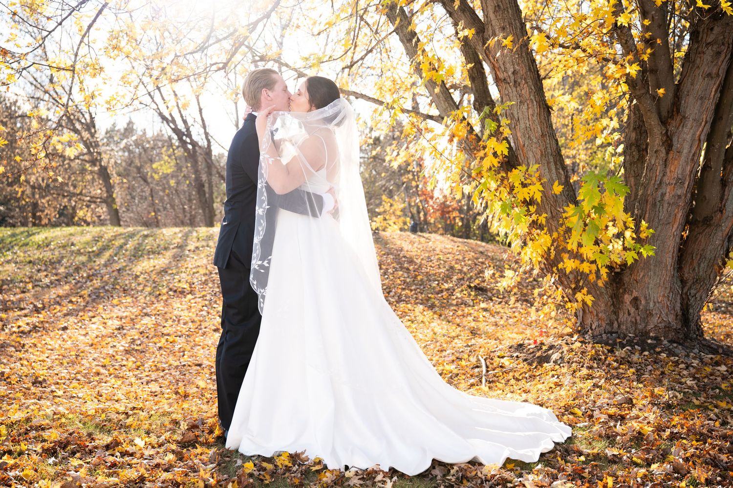 A romantic autumn wedding photo shoot with golden leaves and trees in the background.