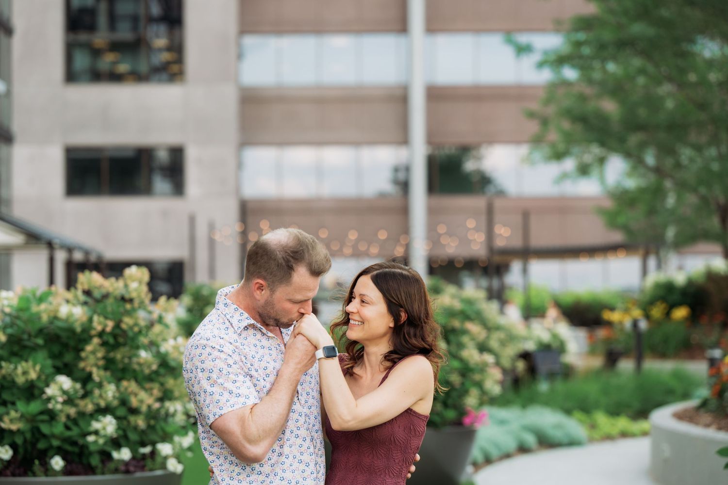 A couple embraces while dancing outdoors near a landscaped garden path.