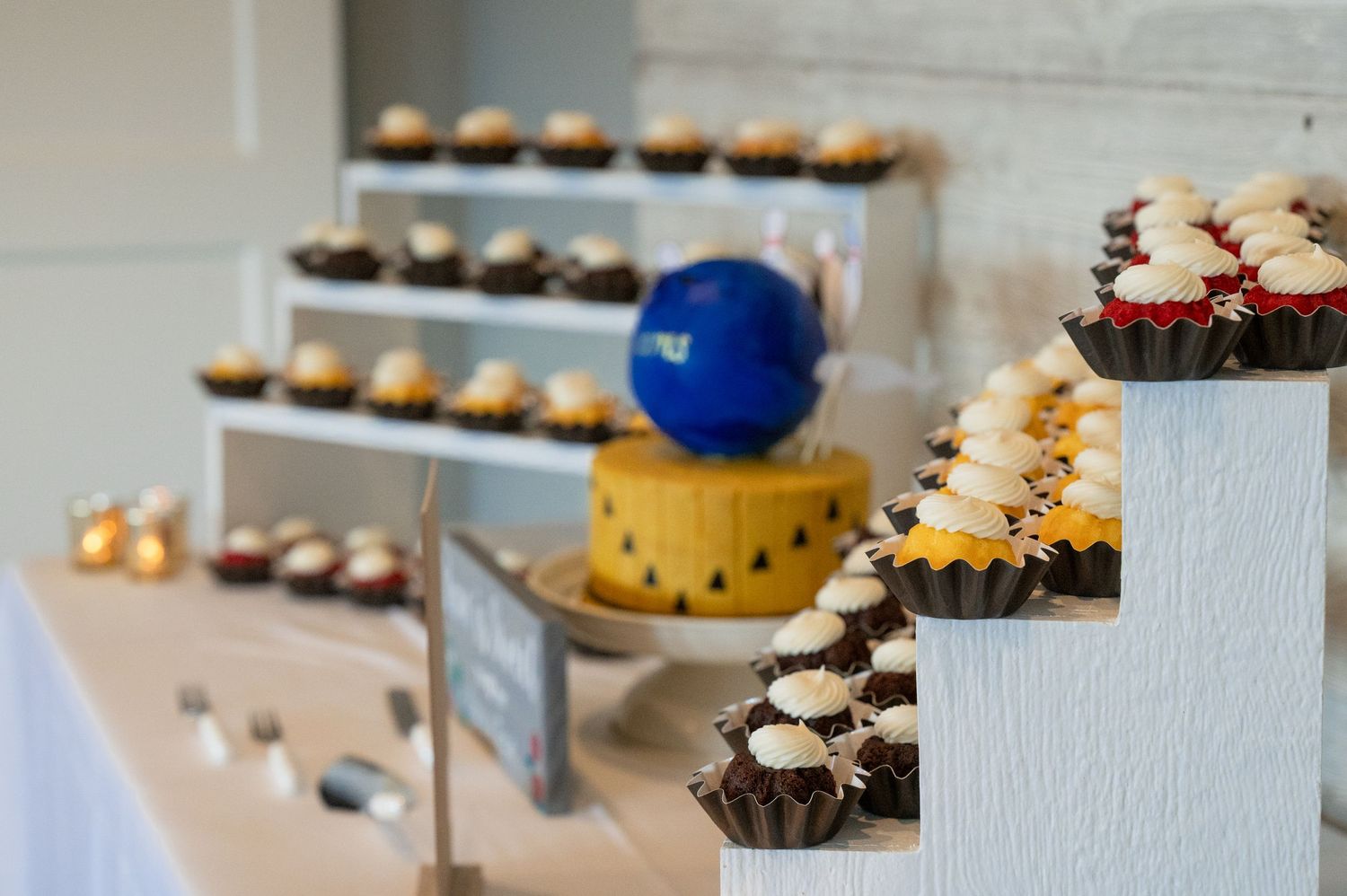 Close-up of a tiered wedding dessert display with assorted cupcakes and a small decorated cake centerpiece.