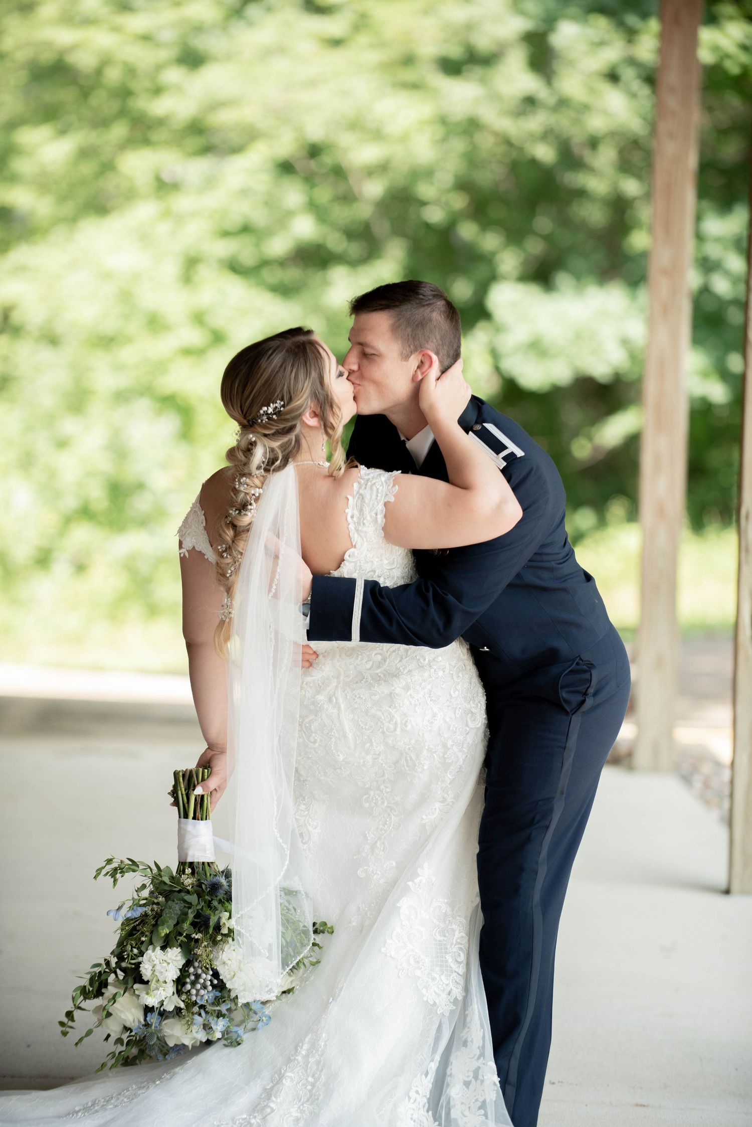 A tender wedding moment captured under a covered outdoor area with soft natural lighting and a bridal bouquet. Zimmerman MN Weddings