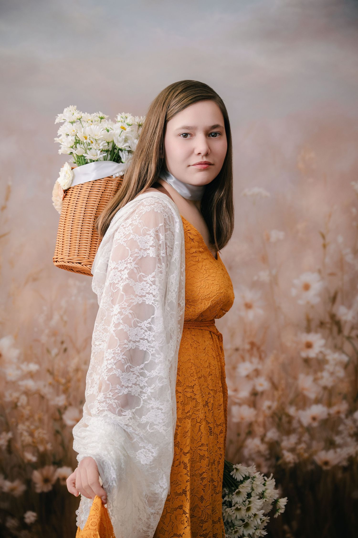 Artistic portrait featuring an mustard colored dress with white lace sleeves and a wicker basket of white flowers against a Whimsical