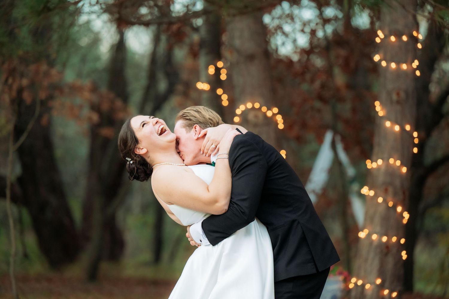 Romantic evening wedding photos with twinkling lights decorating trees in the background.