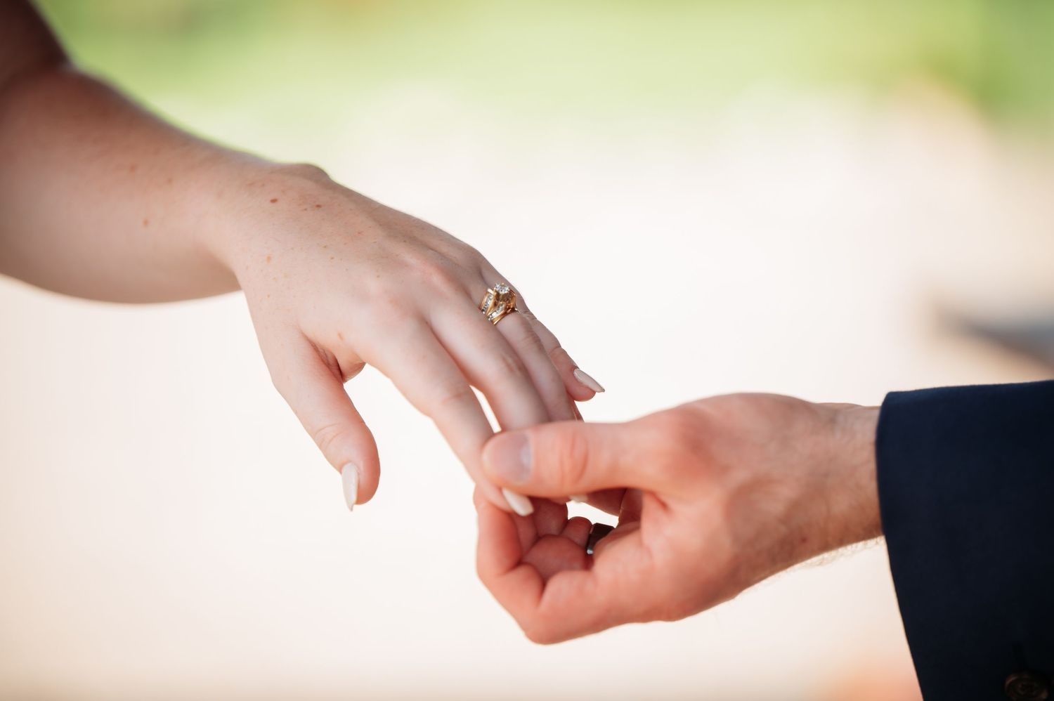 Two hands reaching towards each other against a soft blurred background in a tender gesture. Pease Minnesota Wedding at Northern Lights Ball