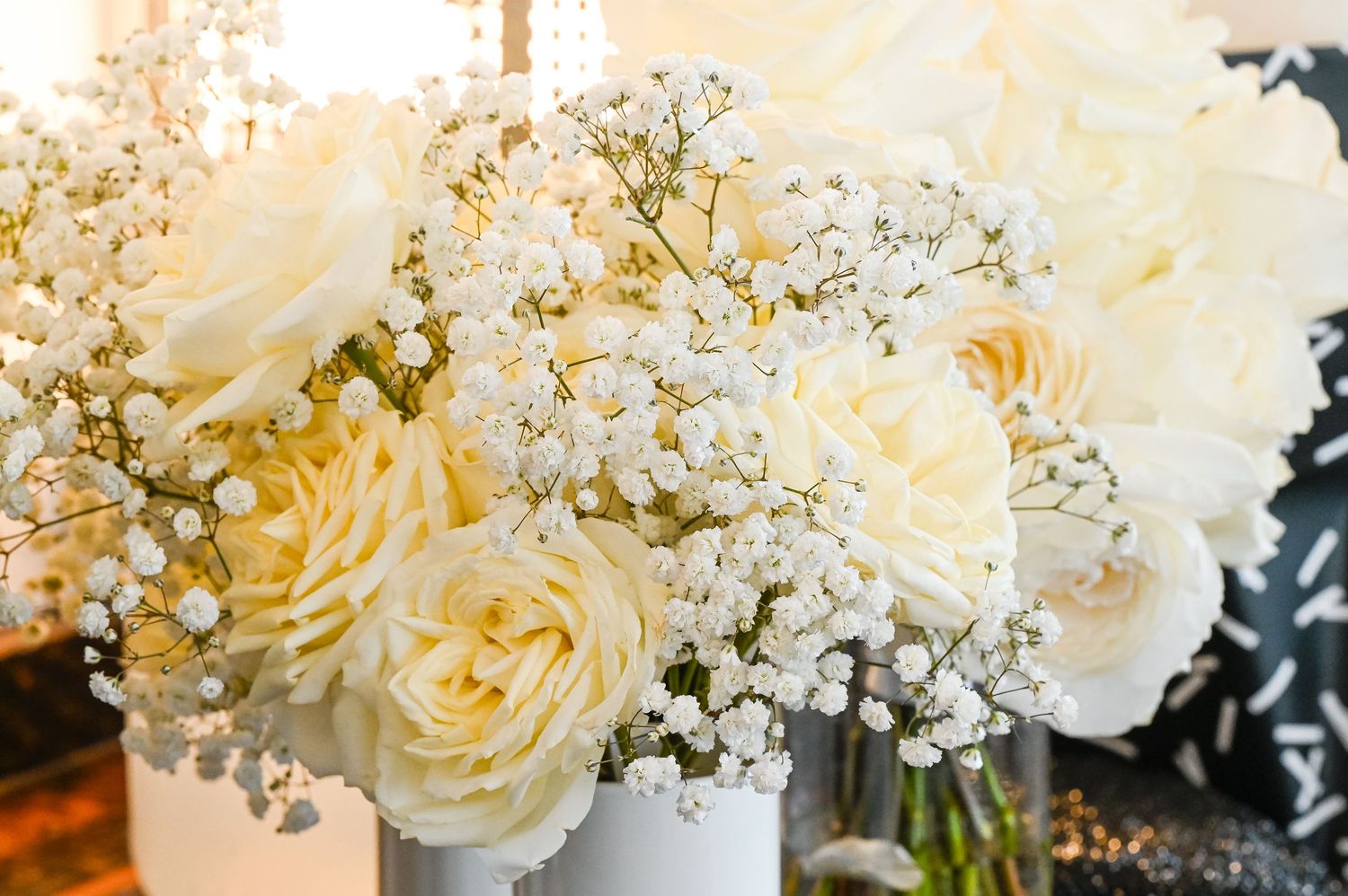 Elegant white roses and baby's breath flowers arranged in a soft, romantic bouquet with warm lighting.