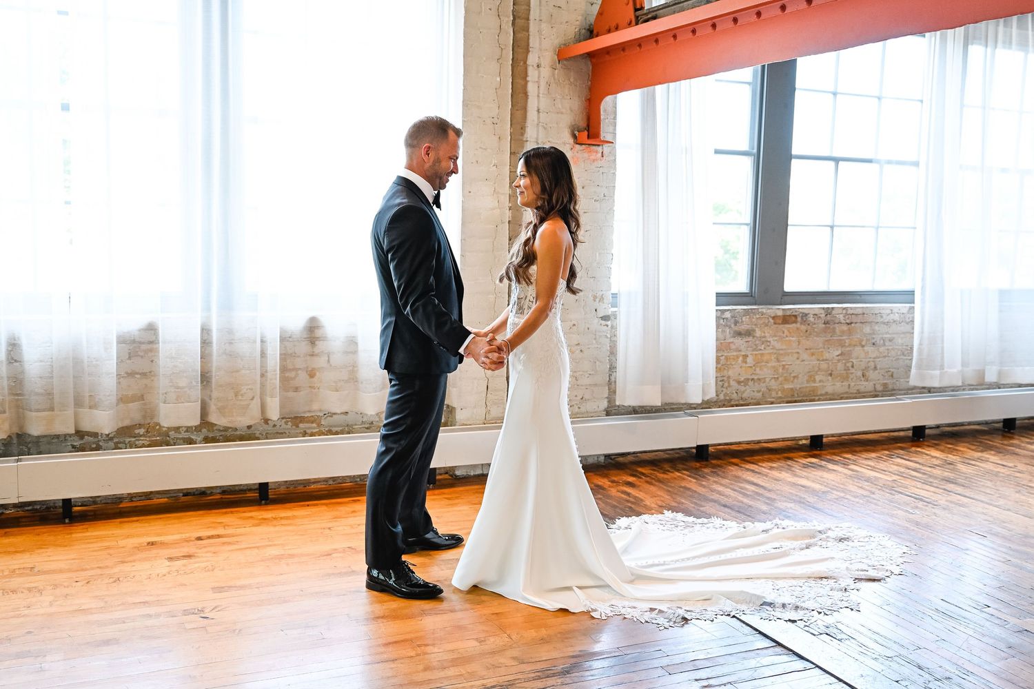 First look moment between couple in an industrial-style venue with brick walls.