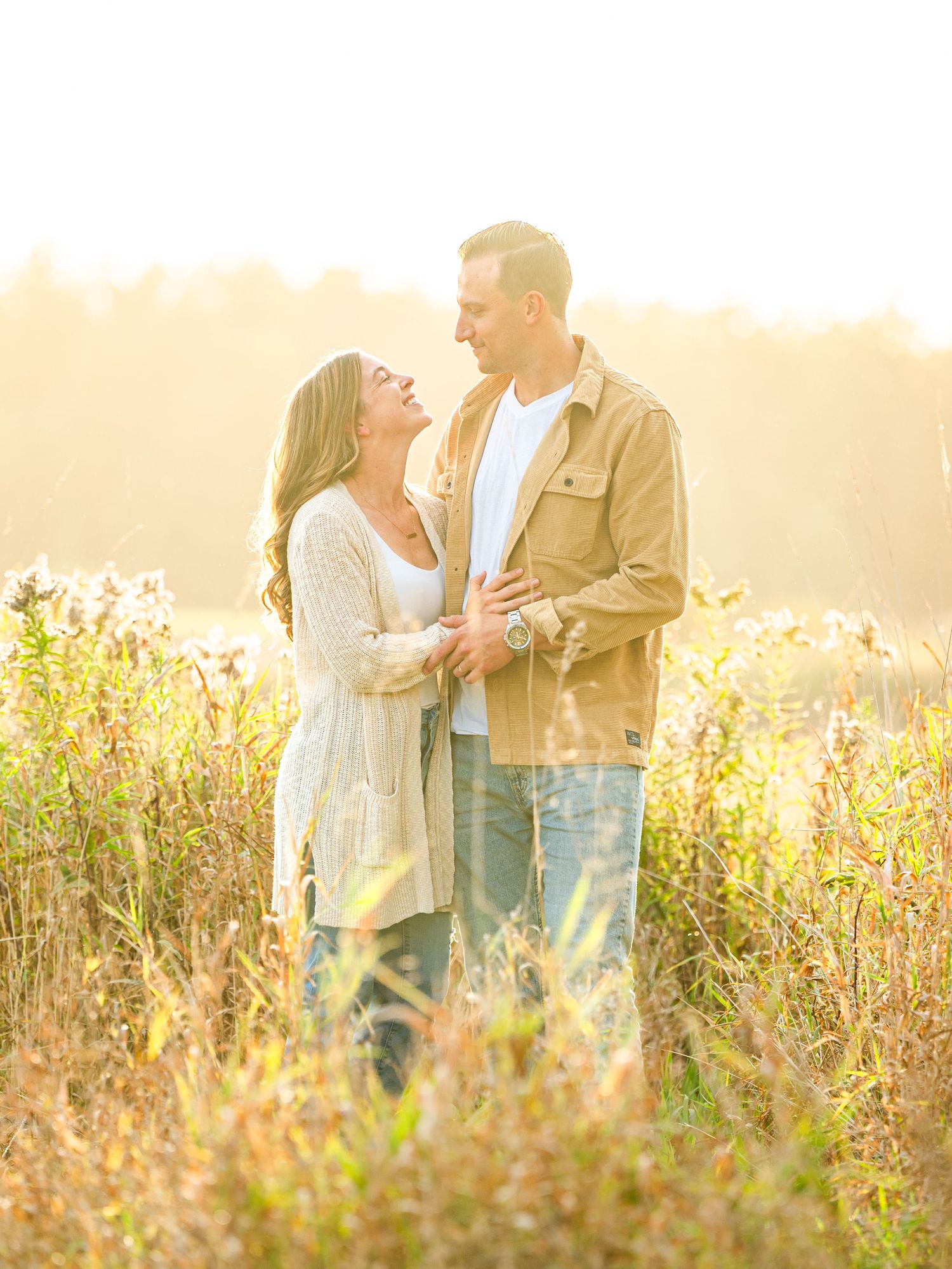 Couple sharing romantic moments in a sunlit wildflower meadow during golden hour.