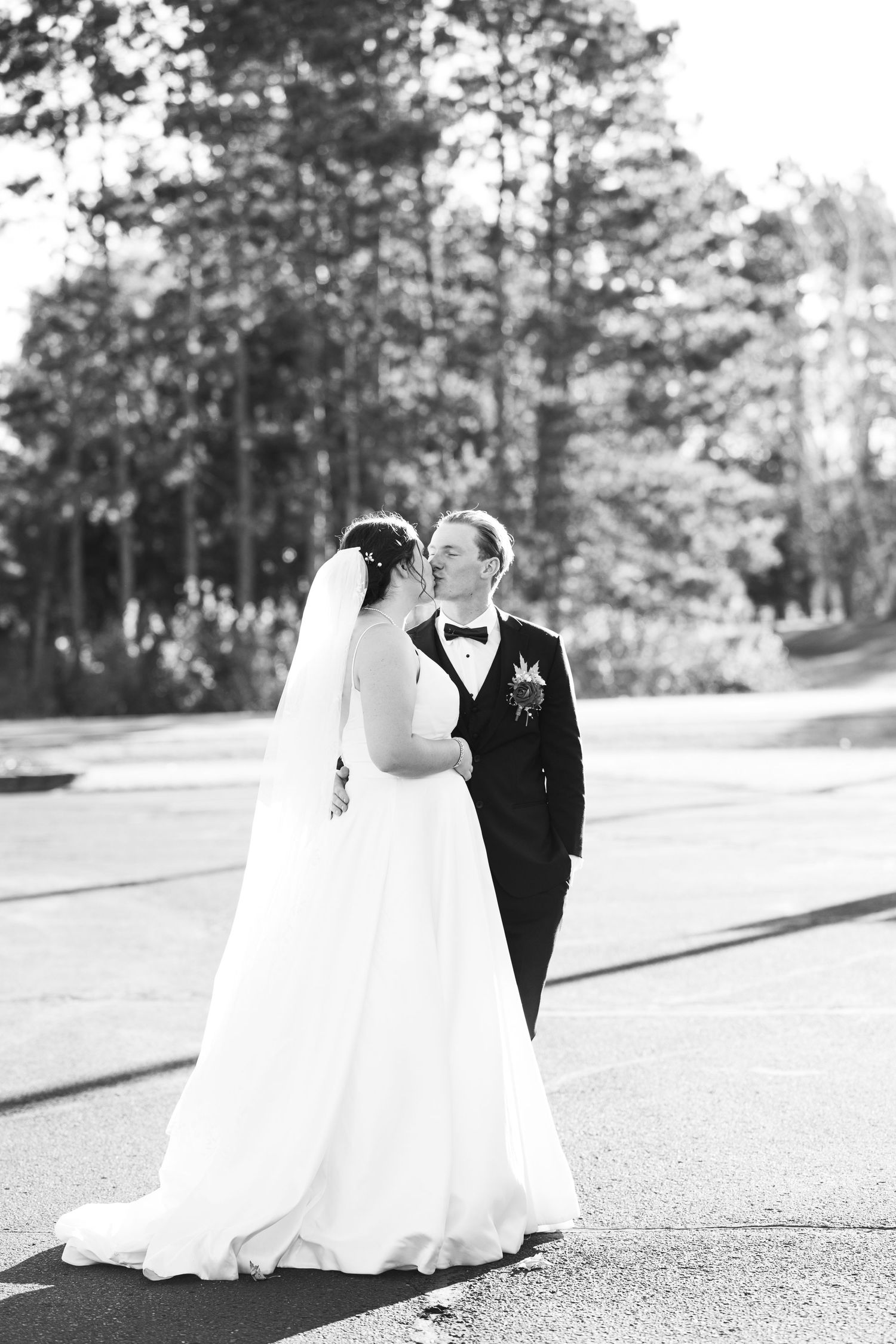 A black and white wedding photo series showing a couple walking together in formal attire on a paved path.