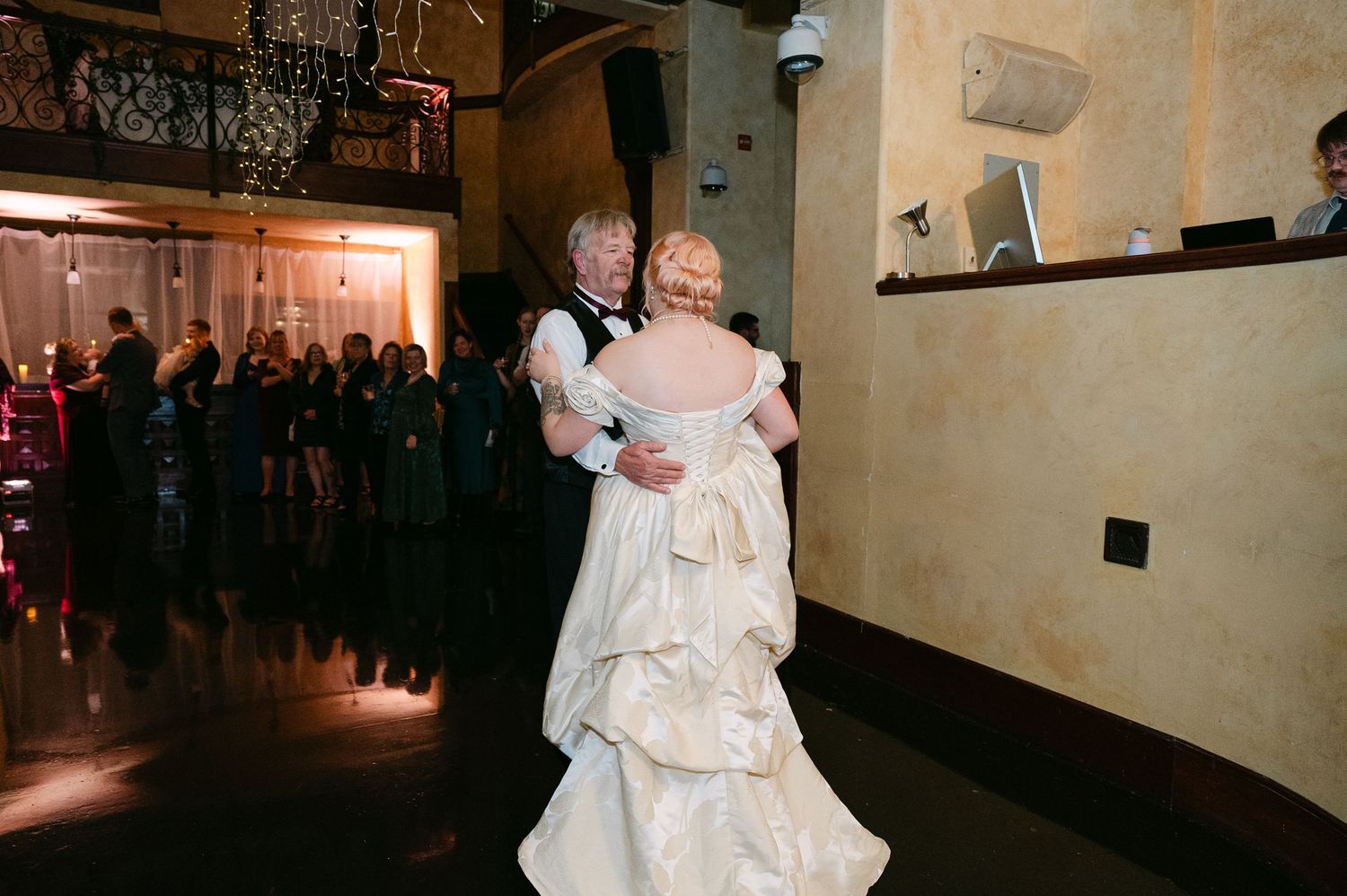 Central MN Wedding Photos | Bride in layered ivory ballgown shares father-daughter dance on dimly lit reception dance floor.