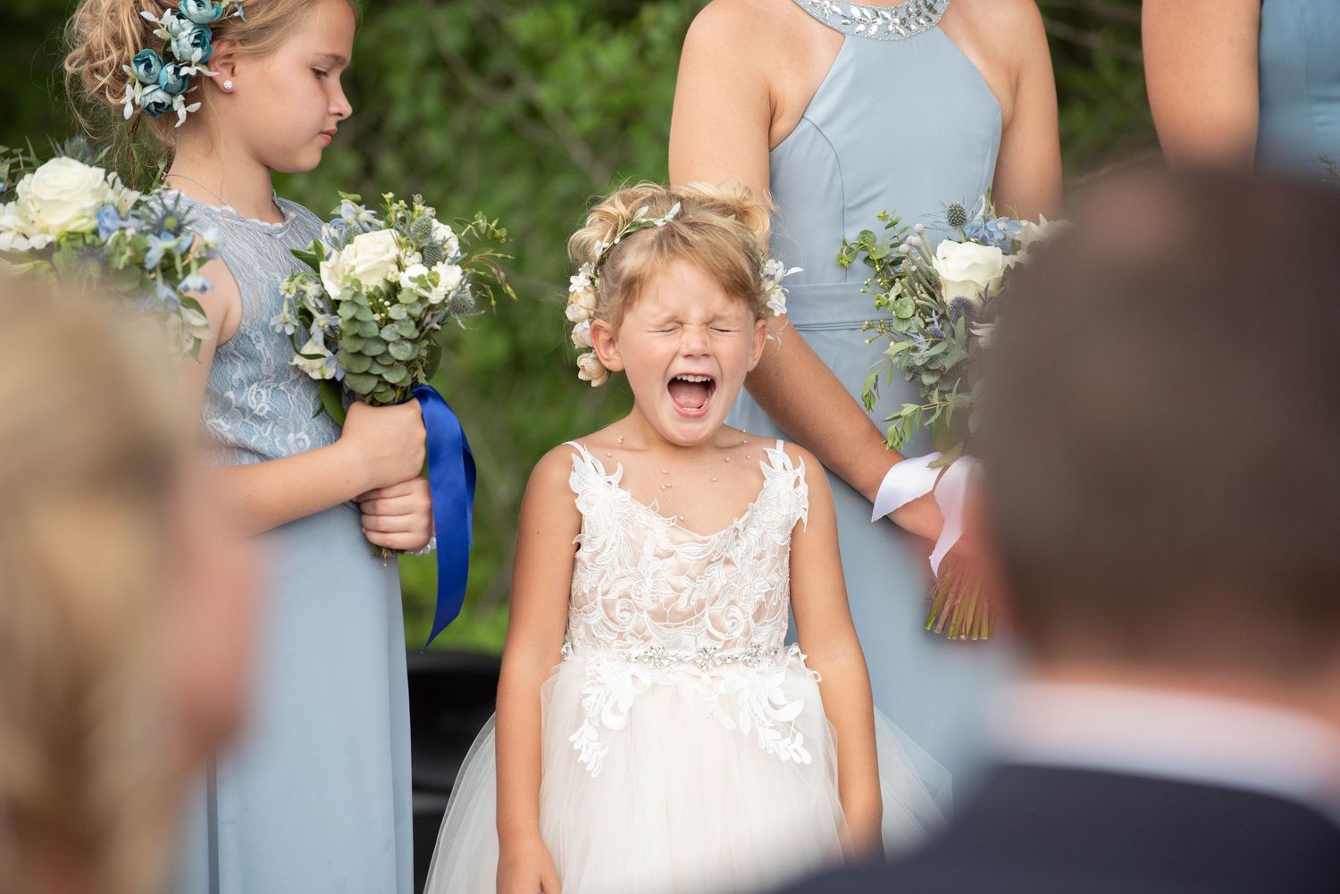 Wedding party members share joyful expressions during an outdoor ceremony with lush greenery in the background. Zimmerman MN Weddings