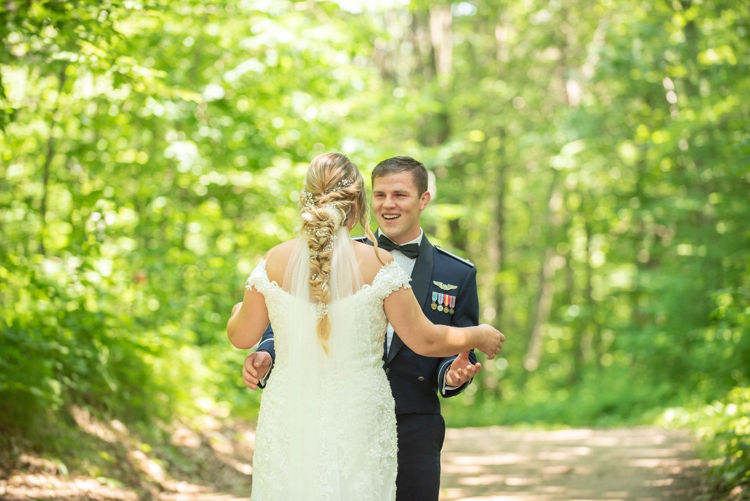 A couple sharing a joyful moment together in a sunlit forest setting during their wedding day. Zimmerman MN Weddings