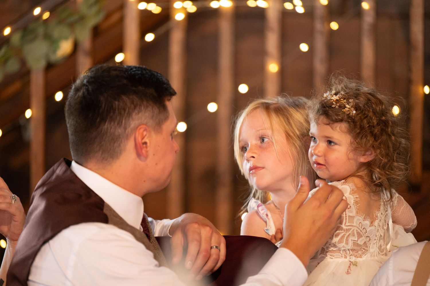 Wedding reception celebration under warm string lights in a rustic setting.