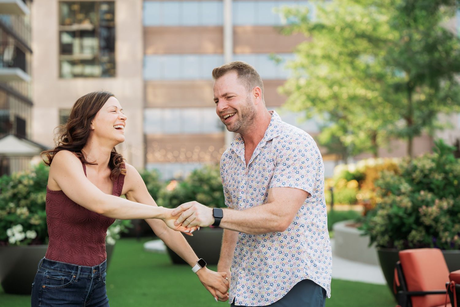 A couple shares a romantic moment dancing together in a garden setting on a sunny day.