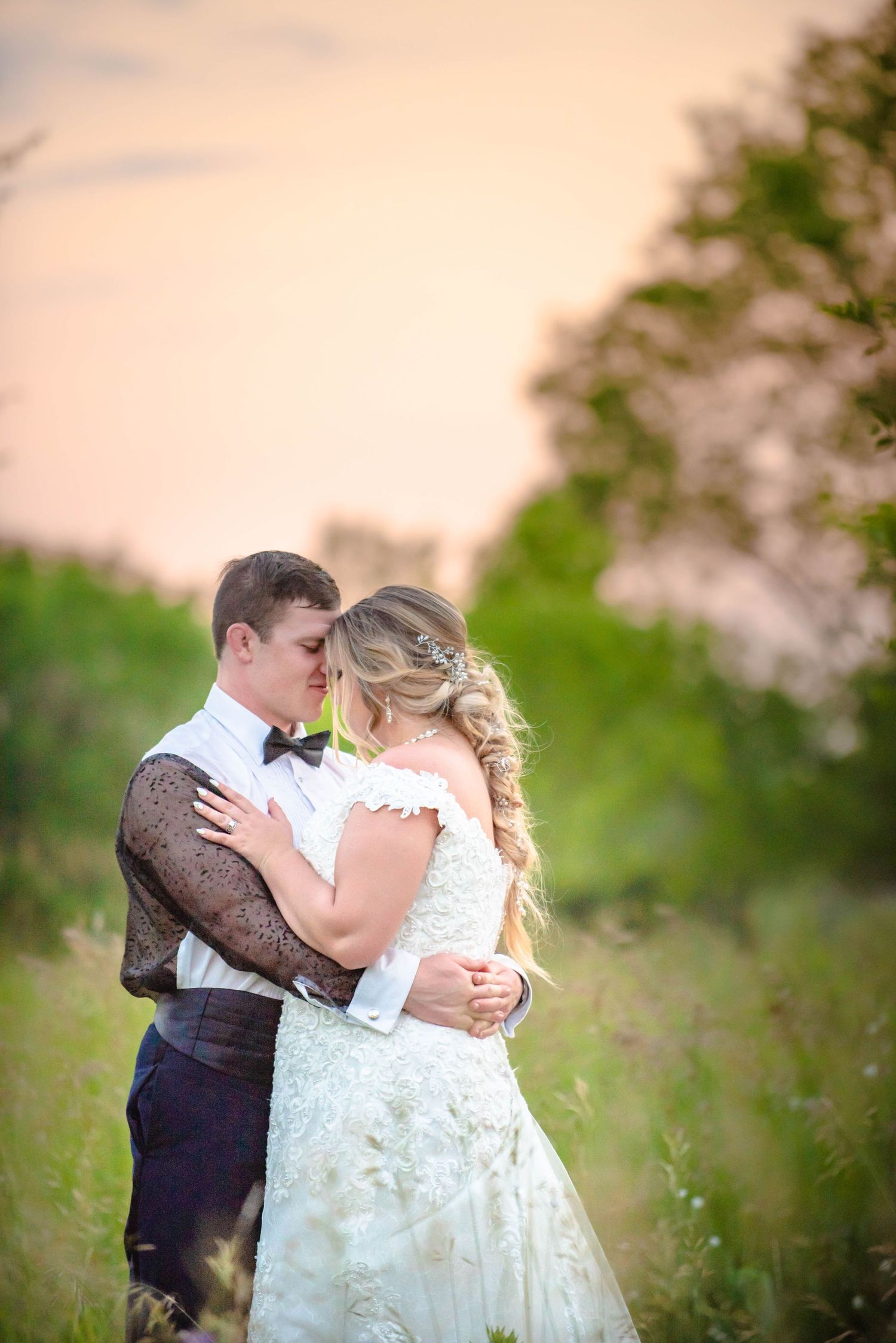 Sunset wedding portrait showing tender moment between newlyweds in tall grass. Zimmerman MN Weddings