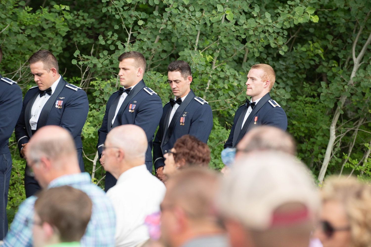 Natural woodland setting with wooden arch structure and gathered audience for outdoor ceremony. Zimmerman MN Weddings